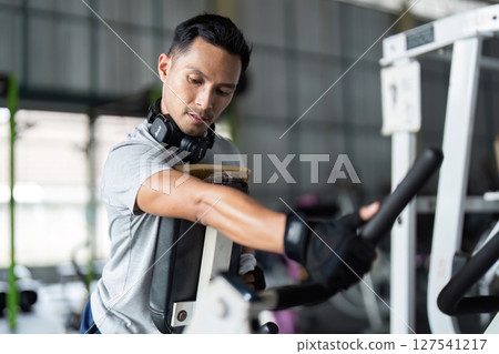 Fitness Training. Male athlete adjusting gym equipment in modern fitness center. Fitness Training. Male athlete adjusting gym equipment in modern fitness center. 127541217