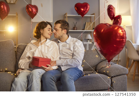 Happy Couple Hugging And Kissing With Gift On Valentine Day Date At Home 127541350