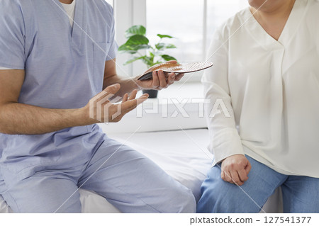 Doctor advises patient about individual orthopedic insoles for correction of flat feet. 127541377