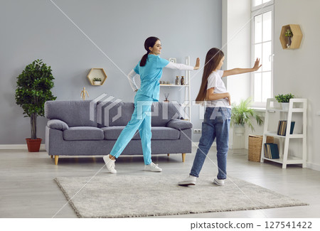 Friendly female nurse helping child girl doing gymnastics and exercises for health. 127541422