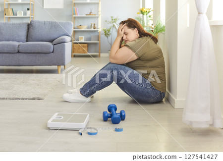 Portrait of depressed upset fat woman covering face with hands at home. 127541427
