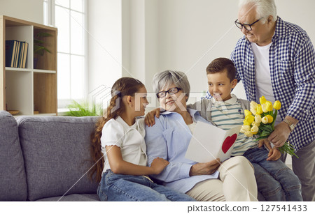 Happy grandmother receives a birthday card and a bouquet of flowers from her loving family 127541433