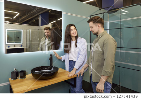 Happy couple looking at bathroom sinks while shopping for plumbing fixtures at DIY store 127541439