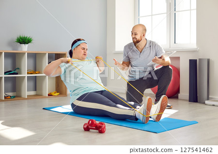 Overweight woman doing fitness workout with her trainer in fitness club Overweight woman doing fitness workout with her trainer in fitness club 127541462