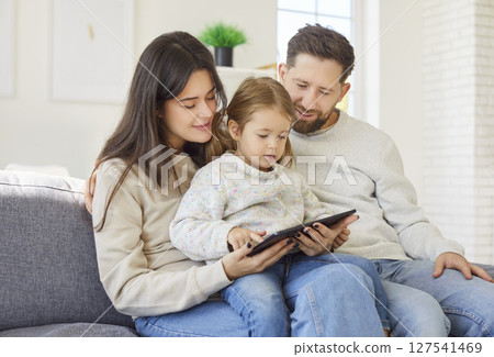 Parents And Daughter Enjoying Online Leisure With Tablet At Home 127541469
