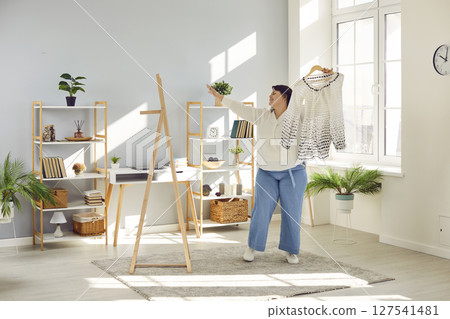 Happy, confident fat woman choosing what to wear, looking in mirror, and having fun Happy, confident fat woman choosing what to wear, looking in mirror, and having fun 127541481