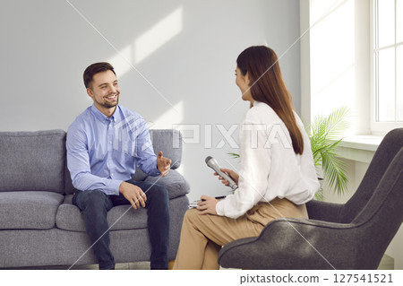 Young woman with microphone interviewing smiling successful businessman 127541521