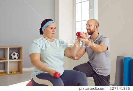Fat woman doing fitness workout with her trainer for in fitness club 127541586