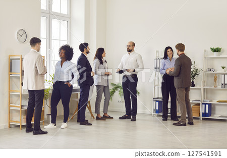 Multicultural group of business people communicate while standing in the office 127541591