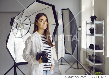 Smiling female professional photographer working in photo studio Smiling female professional photographer working in photo studio 127541614