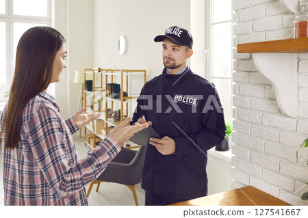 Policeman interviewing female victim after breaking into home 127541667
