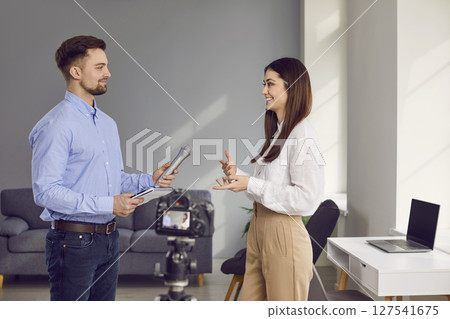 Professional cheerful male journalist with microphone interviewing young businesswoman 127541675