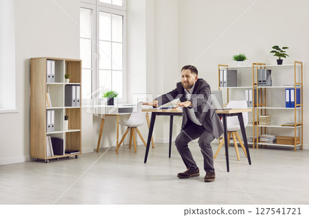 Business man in a suit doing physical exercises during a break at work in the office 127541721