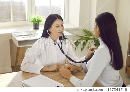 Female physician or cardiologist with stethoscope examining patient's breath or heartbeat 127541746