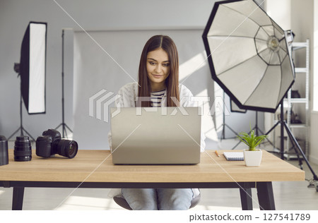 Beautiful woman photographer editing photos on laptop computer in studio 127541789