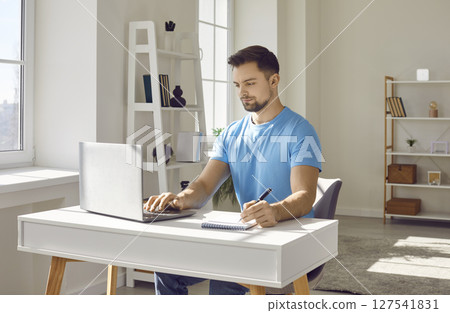 Young business man working at home or at office on a laptop computer sitting at the desk. 127541831