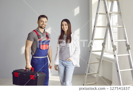 Portrait of happy repairman with toolbox and woman house owner in room with ladder 127541837