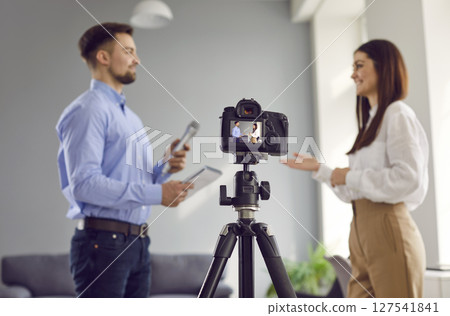 Modern digital video camera recording journalistic interview in television studio 127541841