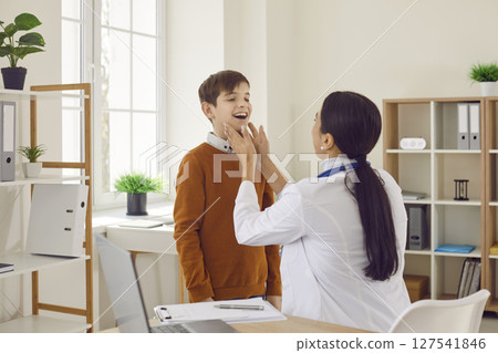 Woman doctor endocrinologist or otolaryngologist is examining her child patient 127541846