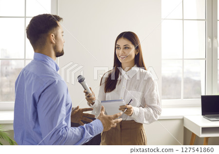 Professional positive female journalist standing with microphone interviewing businessman 127541860