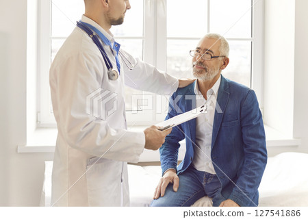Kind young male doctor hand shoulder support close for elderly patient at consultation in hospital 127541886