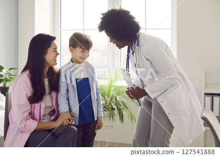 Little boy patient with his mother talking with female paediatrician doctor in clinic. Little boy patient with his mother talking with female paediatrician doctor in clinic. 127541888