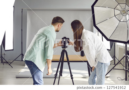 Team of two young professional photographers taking photos in their photo studio Team of two young professional photographers taking photos in their photo studio 127541912
