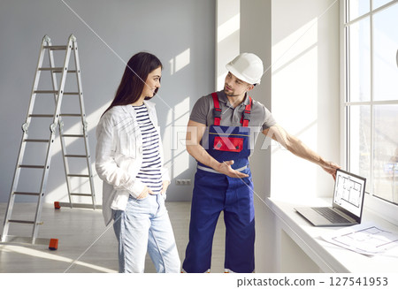 Architect or engineer shows blueprints on laptop and discusses house construction with customer Architect or engineer shows blueprints on laptop and discusses house construction with customer 127541953