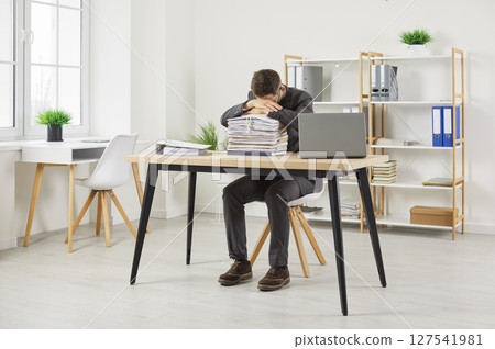 Exhausted worker tired of overworking sleeping on stacks of folders with documents in office. 127541981