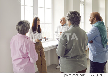 Group of seniors listening psychologist woman speaking on a meeting in nursing home. 127541993