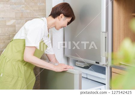 A woman who opens a refrigerator 127542425