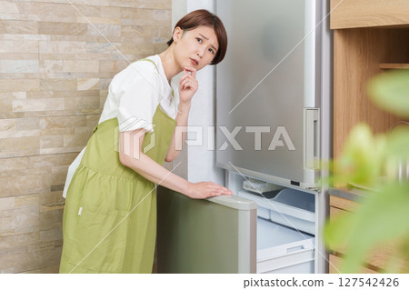 A woman who opens a refrigerator 127542426