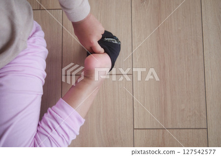 a little girl trying to take off her socks a little girl trying to take off her socks 127542577