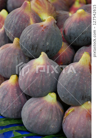 Fresh, succulent figs beautifully displayed alongside vibrant green leaves for decoration 127542615