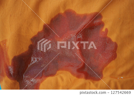 oil spilled on orange fabric with a unique texture 127542669