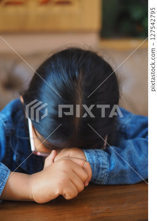 Young girl in thoughtful pose at a cafe table 127542795