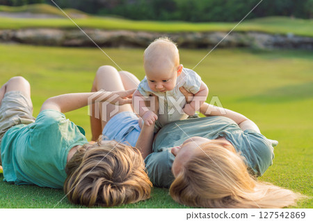 Mother, older son, and newborn baby on a meadow in the park. Family spending quality time together in nature. Parenthood, love, and family bond concept Mother, older son, and newborn baby on a meadow in the park. Family spending quality time together in nature. Parenthood, love, and family bond concept 127542869