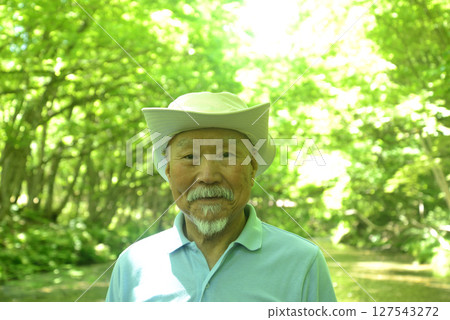 Smiling elderly man enjoying forest bathing in the fresh greenery Smiling elderly man enjoying forest bathing in the fresh greenery 127543272