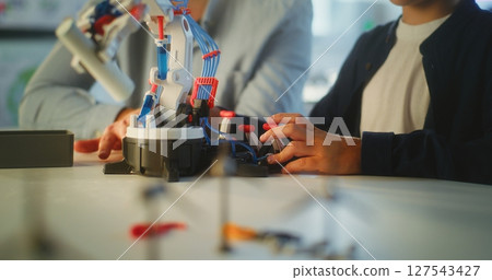 Close Up of Boy Studying Robotic Arm Model with Teacher in Primary School Close Up of Boy Studying Robotic Arm Model with Teacher in Primary School 127543427