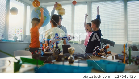 Young Teacher and Kids Doing Team Huddle Gesture in Multiethnic Classroom 127543429