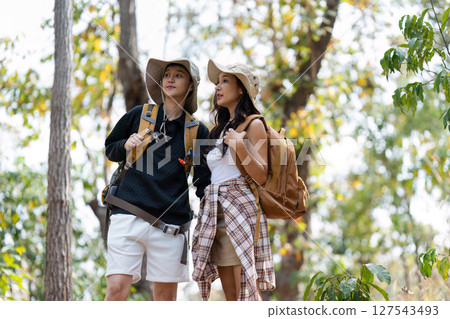 Happy LGBT Lesbian couple Travelers Hiking with Backpacks in waterfall Trail. LGBT Lesbian Couple Hikers with backpacks walks in mountains in vacation 127543493
