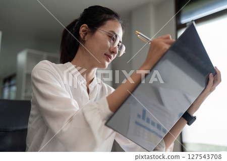 Portrait of an Asian woman working on folder in a modern office. Make an account analysis report Portrait of an Asian woman working on folder in a modern office. Make an account analysis report 127543708