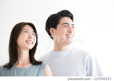一對身著夏裝、面帶微笑的夫婦的特寫鏡頭,他們仰望著白色背景 一對身著夏裝、面帶微笑的夫婦的特寫鏡頭,他們仰望著白色背景 127545151