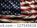 Close-up of a weathered and wrinkled American flag, showcasing the texture of its fabric and the enduring spirit of patriotism. 127545618