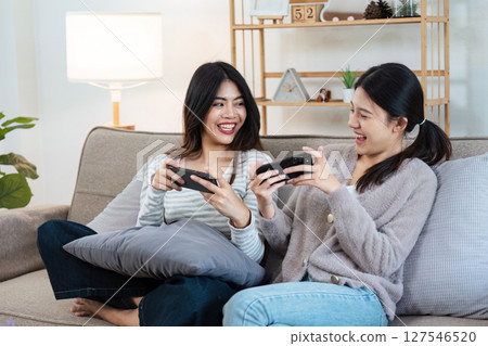 Happy woman lesbian gay lgbt couple enjoying fun gaming session on the couch at home. lgbt concept Happy woman lesbian gay lgbt couple enjoying fun gaming session on the couch at home. lgbt concept 127546520