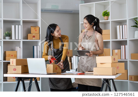 Young business entrepreneur sealing a box with tape. Preparing for shipping, Packing, online selling, e-commerce concept Young business entrepreneur sealing a box with tape. Preparing for shipping, Packing, online selling, e-commerce concept 127546561