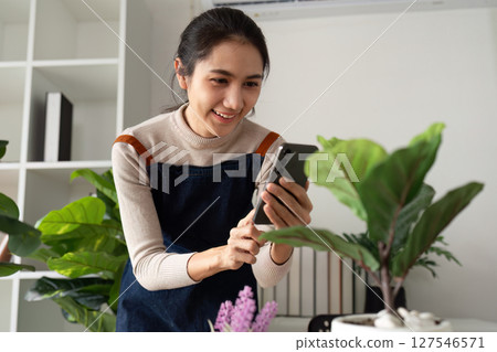 woman hold mobile and take picture of newly plant tree. eco friendly home 127546571