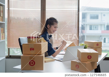 Young business entrepreneur using laptop. Preparing for shipping, online selling, e-commerce concept Young business entrepreneur using laptop. Preparing for shipping, online selling, e-commerce concept 127546685