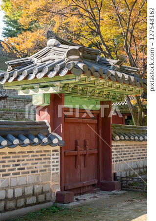 Korean traditional stone wall in Changdeokgung palace with beautiful autumn foliage. 127548162