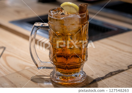 A glass of whiskey with lemon and cinnamon, on the table A glass of whiskey with lemon and cinnamon, on the table 127548263